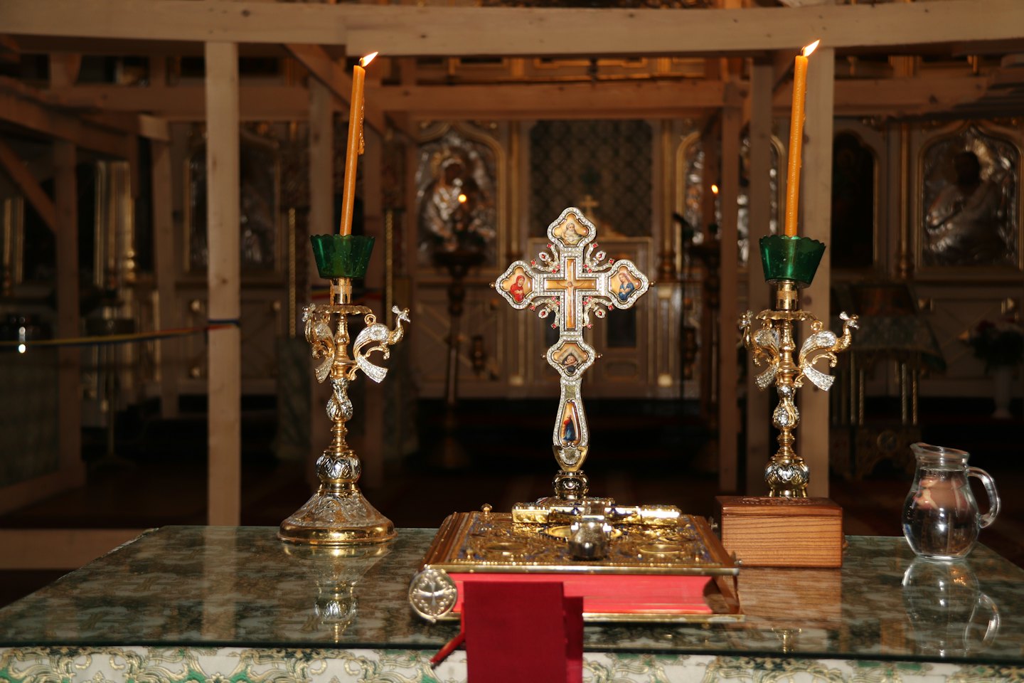 Religious artifacts and lit candles arranged on a marble table.