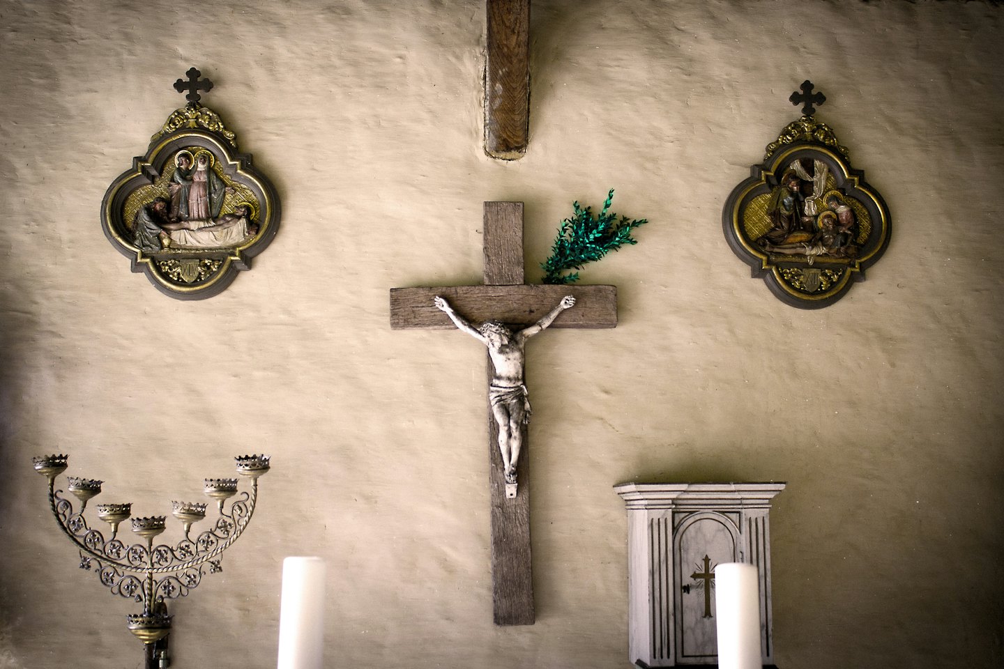 Religious artifacts including a crucifix and candelabra on a wall.